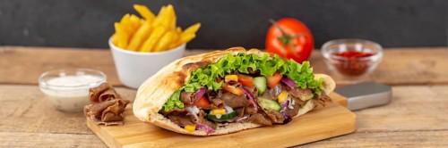 Doener Kebab Doner Kebap half fast food meal in pita bread with fries on wooden board Panorama in Stuttgart