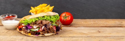 Doener Kebab Doner Kebap fast food meal in pita bread menu with fries on wooden board Panorama with text free space Copyspace in Stuttgart