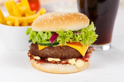 Hamburger cheeseburger fast food meal menu with fries and coke drink on wooden board in Stuttgart