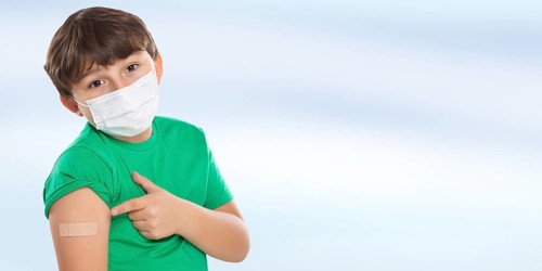 Child boy pointing finger at plaster during children vaccination mask against coronavirus corona virus text free space copyspace in Stuttgart