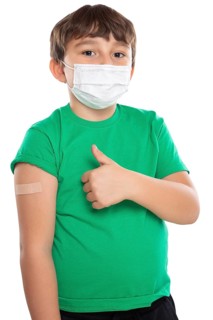 Child boy with plaster at children vaccination mask showing thumbs up against corona virus corona virus isolated exempt in Stuttgart