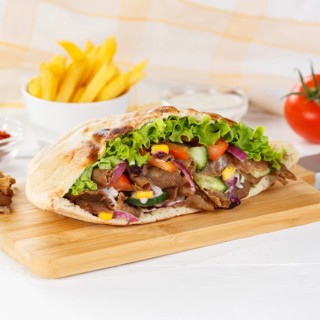 Doener Kebab Doner Kebap half fast food meal in pita bread with fries on wooden board square in Stuttgart