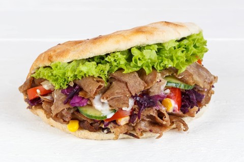 Doener Kebab Doner Kebap half fast food meal in pita bread panorama on wooden board in Stuttgart