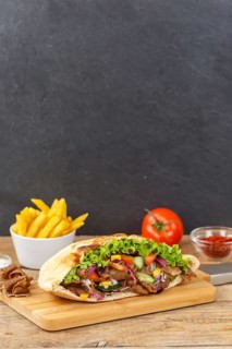 Doener Kebab Doner Kebap half fast food meal in pita bread with fries on wooden board in Stuttgart