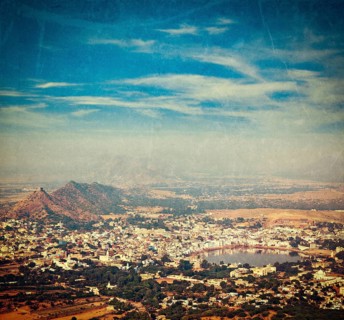 Vintage retro hipster style travel image of Holy city Pushkar aerial view from Savitri temple with grunge texture overlaid. Rajasthan