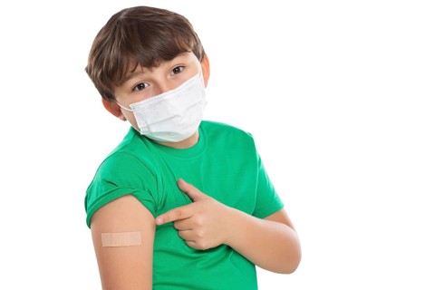 Child boy pointing finger at plaster during children vaccination mask against coronavirus corona virus isolated exempt in Stuttgart