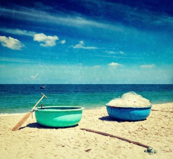 Vintage retro hipster style travel image of fishing coracle boats on beach with grunge texture overlaid. Mui Ne