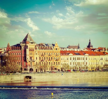 Vintage retro hipster style travel image of Prague Stare Mesto embankment view from Charles bridge on sunset. Prague
