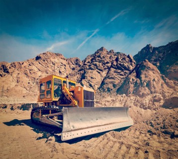 Vintage retro effect filtered hipster style travel image of Bulldozer doing road construction in Himalayas. Ladakh