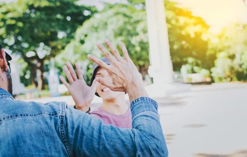 Close up of smiling people shaking hands in a park. Concept of two friends greeting each other with a handshake on the street