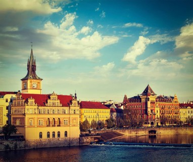 Vintage retro hipster style travel image of Prague Stare Mesto embankment view from Charles bridge on sunset. Prague