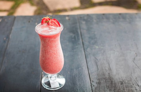 Strawberry smoothie on wooden table. Strawberry milkshake on wooden table with blurred background. Close up of healthy strawberry smoothie on wood with blurred background
