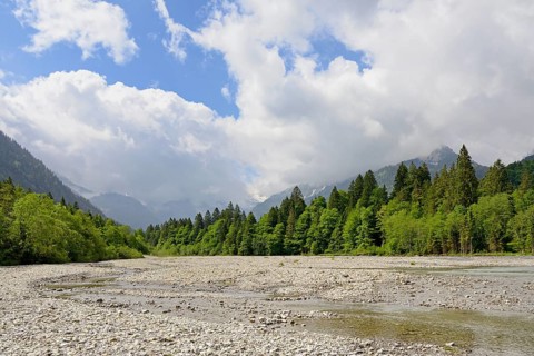 View of the Stillach river landscape and the cloud-covered mountains