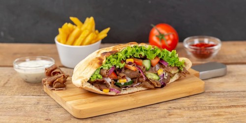 Doener Kebab Doner Kebap half fast food meal in pita bread with fries on wooden board Panorama in Stuttgart