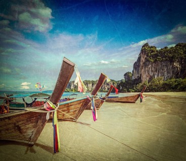 Vintage retro hipster style travel image of Long tail boats on tropical beach