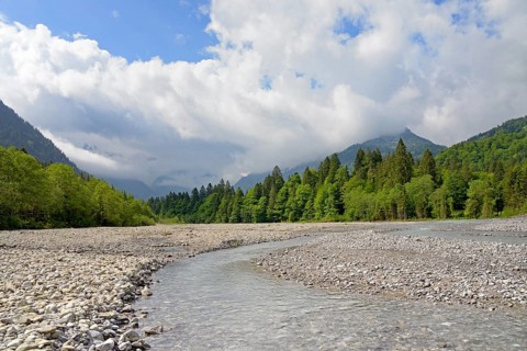 View of the Stillach river landscape and the cloud-covered mountains