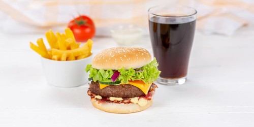 Hamburger cheeseburger fast food meal menu with fries and coke drink on wooden board Panorama in Stuttgart