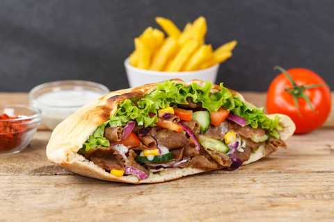 Doener Kebab Doner Kebap fast food meal in pita bread menu with fries on wooden board in Stuttgart