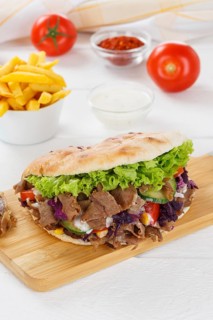 Doener Kebab Doner Kebap fast food meal in pita bread menu with fries on kitchen board in Stuttgart