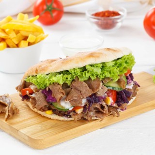 Doener Kebab Doner Kebap fast food meal in pita bread menu with fries on kitchen board square in Stuttgart