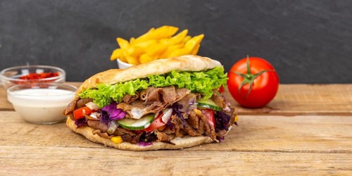 Doener Kebab Doner Kebap fast food meal in pita bread menu with fries Panorama on wooden board with text free space Copyspace in Stuttgart