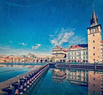Vintage retro hipster style travel image of Prague Stare Mesto embankment view from Charles bridge with grunge texture overlaid. Prague