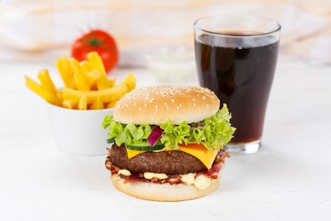 Hamburger cheeseburger fast food meal menu with fries and coke drink on wooden board in Stuttgart