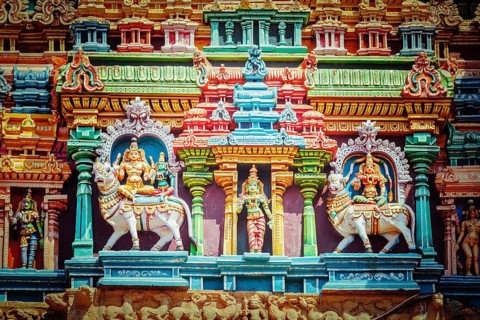 Vintage retro hipster style travel image of Shiva and Parvati on bull images. Sculptures on Hindu temple gopura tower. Minakshi Temple