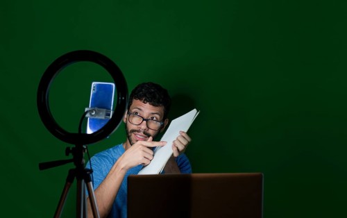 Man giving classes in a video call. Online classes concept. Man giving online classes with phone. Guy with laptop making video blog on phone. Guy on a video call working from home