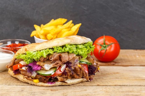 Doener Kebab Doner Kebap fast food meal in pita bread menu with fries on wooden board with text free space copyspace in Stuttgart