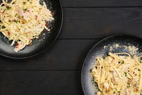 Top view of two plate with pasta with ham and mushrooms