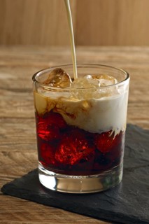 Pouring cream into cocktail White Russian. Vodka