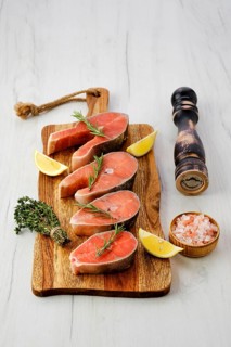 Overhead view of raw trout steaks on wooden cutting board ready for cooking