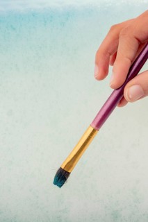 Hand holding a paint brush on water covered with foam