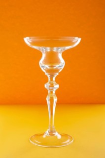 Empty glass for cocktail or dessert on orange background
