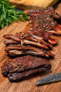 Top view of grilled lamb breast ribs on wooden cutting board