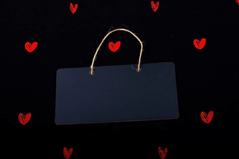 Rectangular shaped black notice board and red hearts on black background