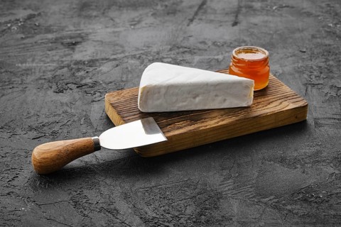 Piece of soft brie or camembert cheese on cutting board