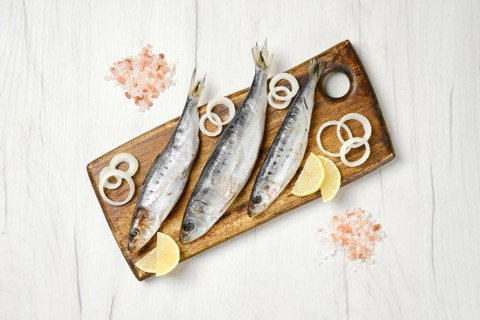 Top view of salted iwashi herring fish marinated in spice on wooden cutting board