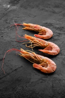 Three fresh raw prawns on wooden background