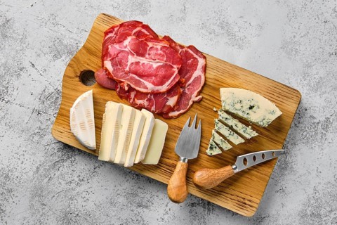 Top view of wooden cutting board with smoked bacon