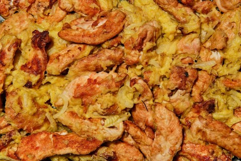 Closeup view of chicken stripes baked with cheese and onion