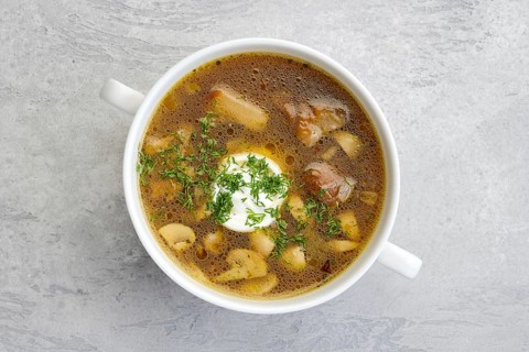 Top view of mushrooms and potato soup with sour cream