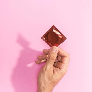 Close up man holding up red condom