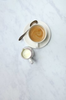 Cup with coffee and pot of milk