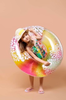 Cute child in sundress and straw hat with swimming ring playing in studio