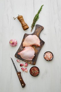 Raw chicken thighs on wooden cutting board ready for cooking