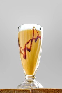 Low angle view of glass of banana smoothie on wooden table