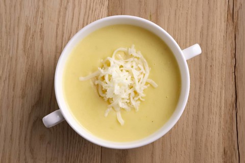 Top view of soup puree with cheese and mushrooms on wooden table