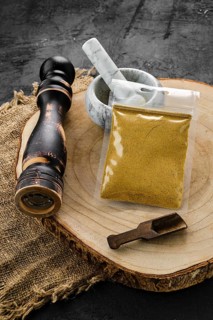 Wooden cross section with curry in plastic package and stone mortar and mill